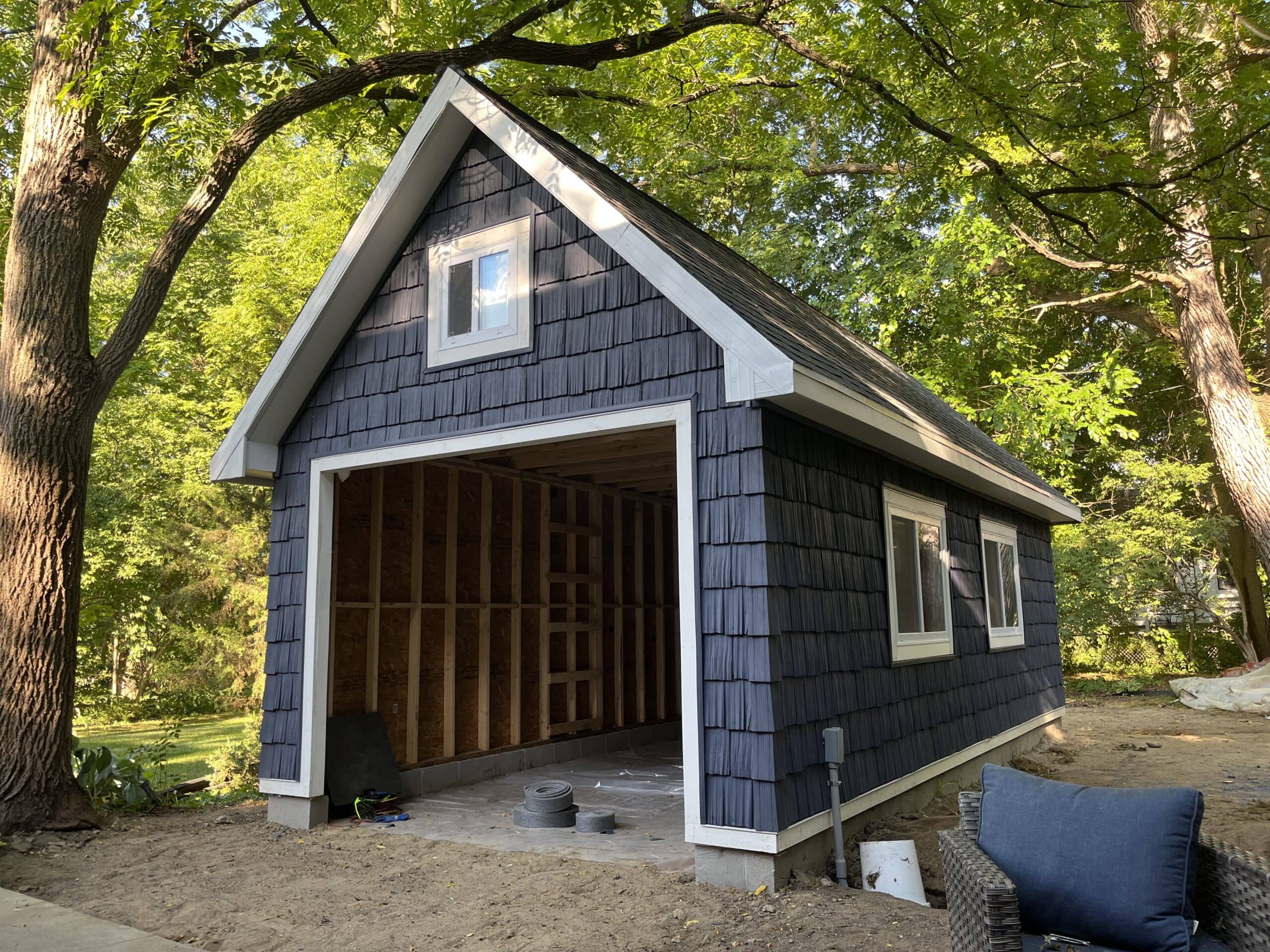 Detached garage outbuilding with blue siding and the front framing open