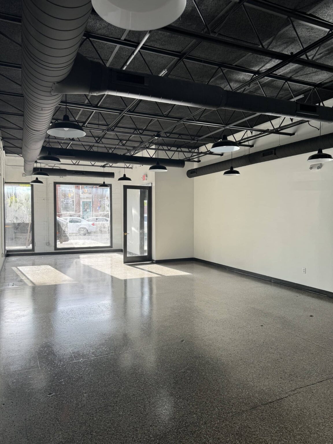Saline commercial space during the build-out with new white walls, a bare concrete floor and the open ceiling painted black