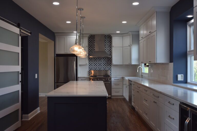 White kitchen with a navy island and patterned backsplash