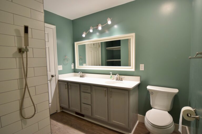 Sage green bathroom with white subway tile and wood vanity
