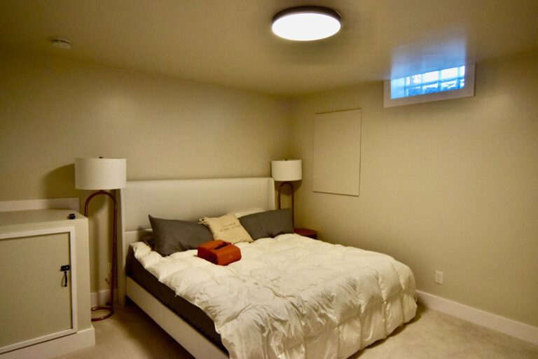 Basement guest bedroom with a made bed and warm lighting