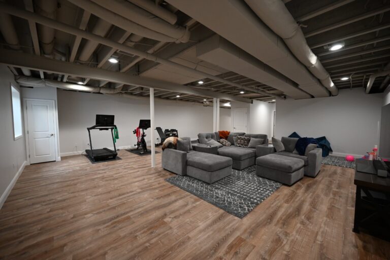 Finished basement rec room with a gray sectional and TV