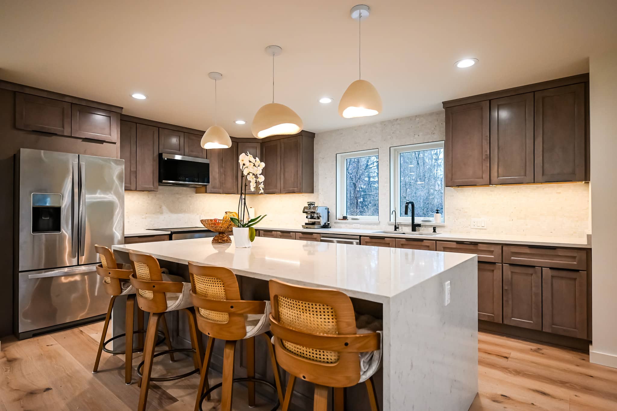 Modern kitchen with white cabinets, marble countertops, and elegant pendant lighting in Southeast Michigan