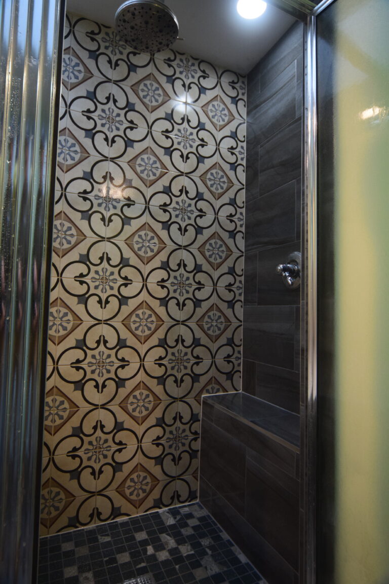 Patterned tile floor beside a dark tiled shower