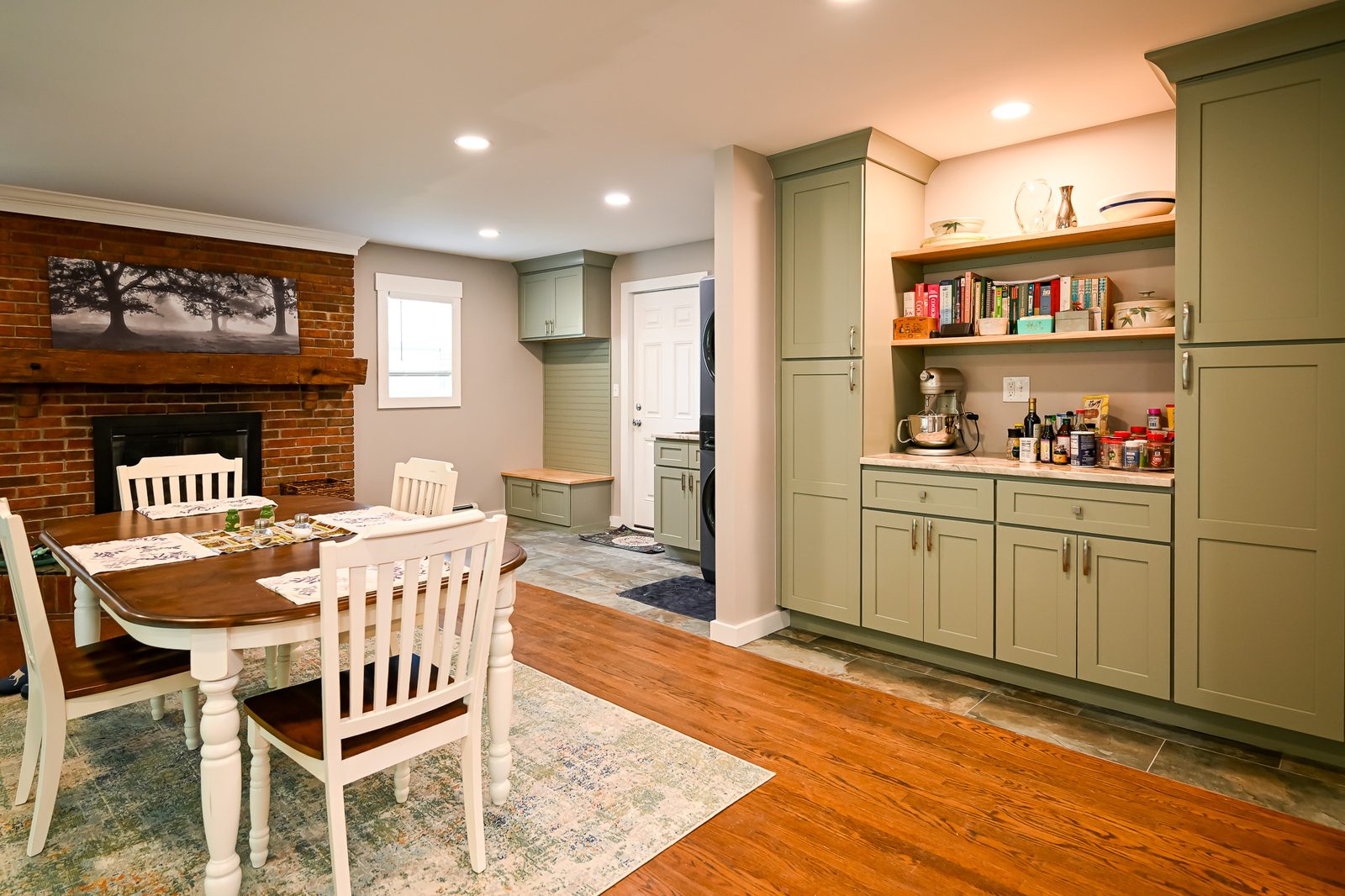 Open floor plan with a dining area, brick fireplace, and custom cabinets flowing into the kitchen