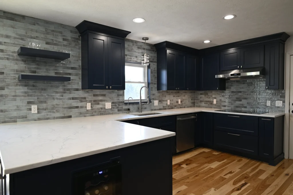 Navy kitchen with open floating shelves, stone countertops, and a run of new base cabinets
