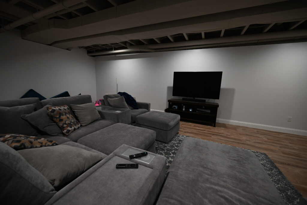 Finished basement home theater with a sectional sofa and a wall-mounted television