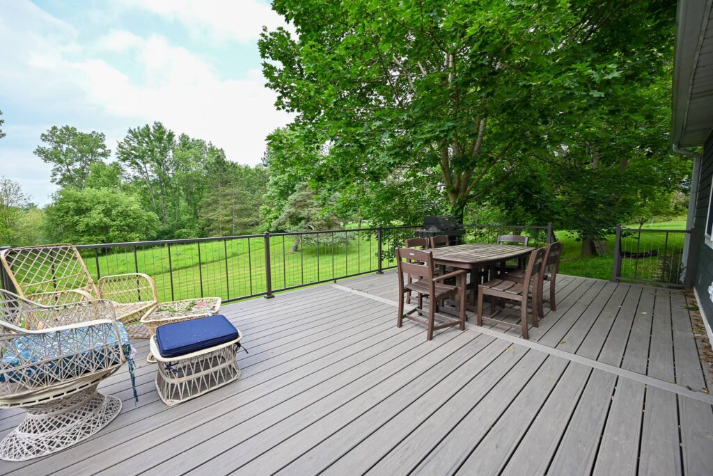 Wood backyard deck with outdoor dining furniture overlooking a wooded yard