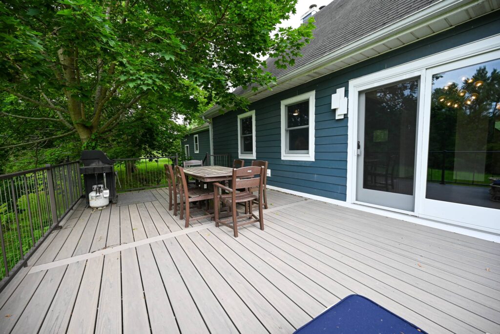 Composite deck and patio with an outdoor dining set against a navy blue sided house