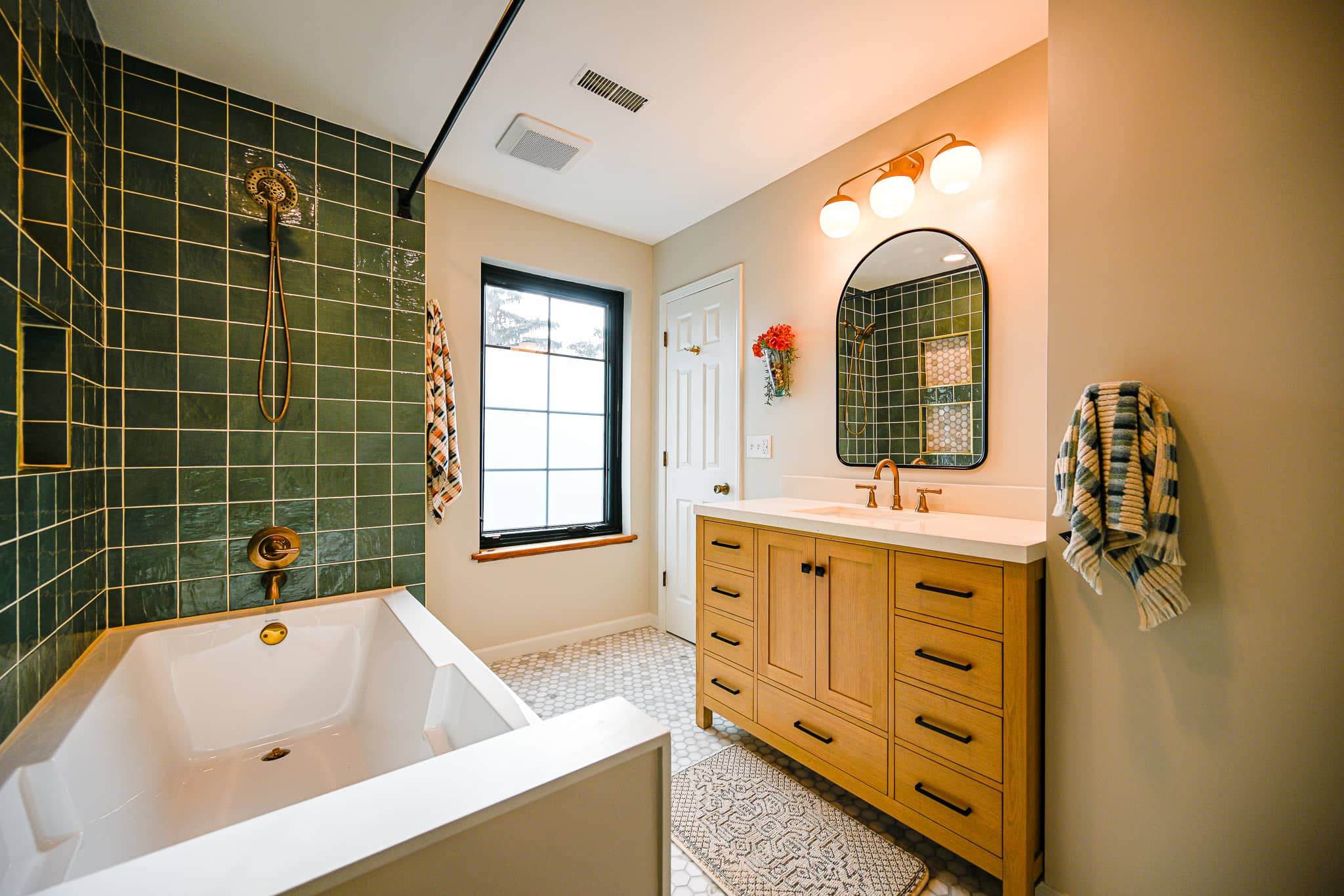 Dexter bathroom seen from the tub end showing the vanity, arched mirror and brass three globe light