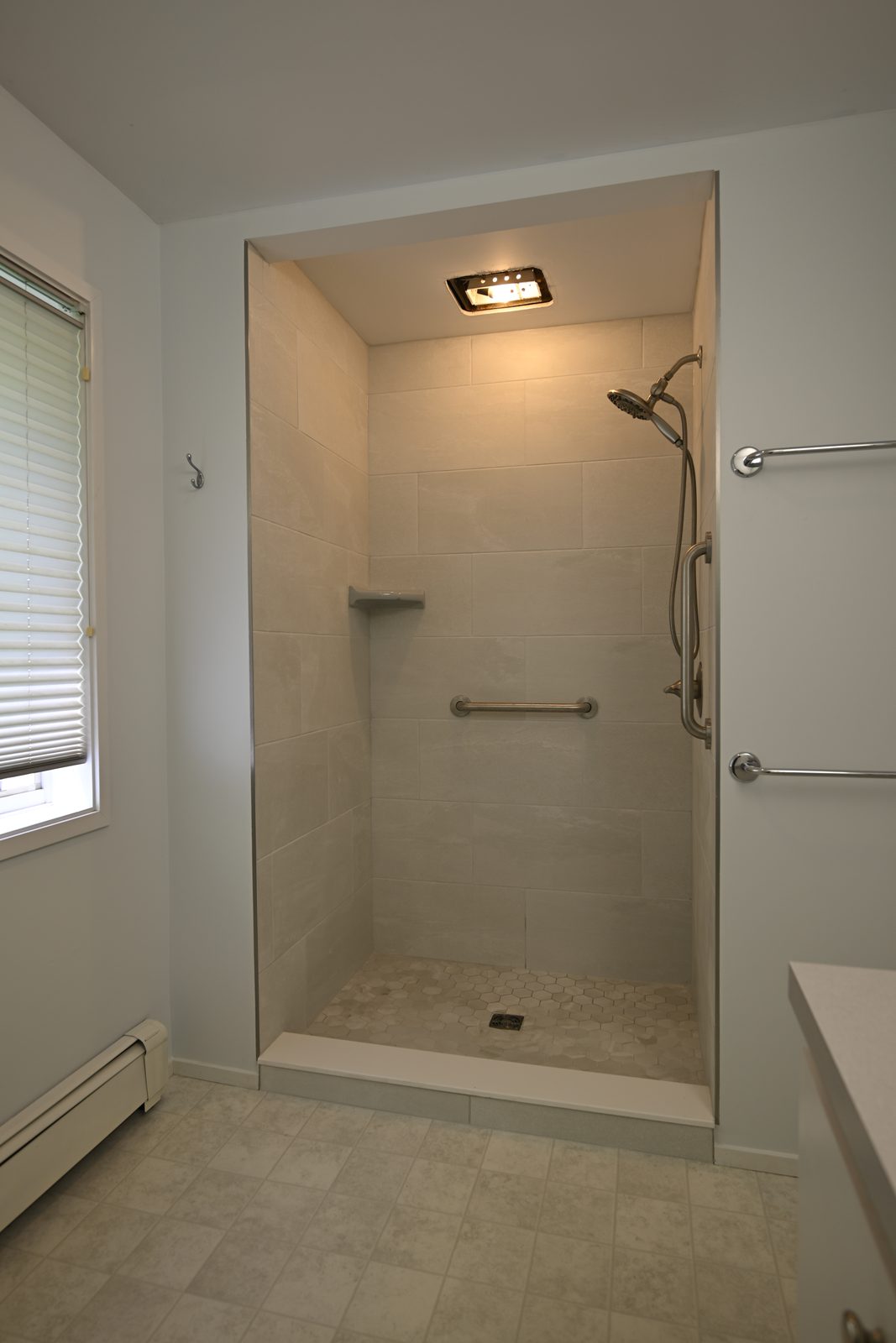 Finished walk-in shower beside a window with new sheet vinyl flooring in an Ann Arbor bathroom
