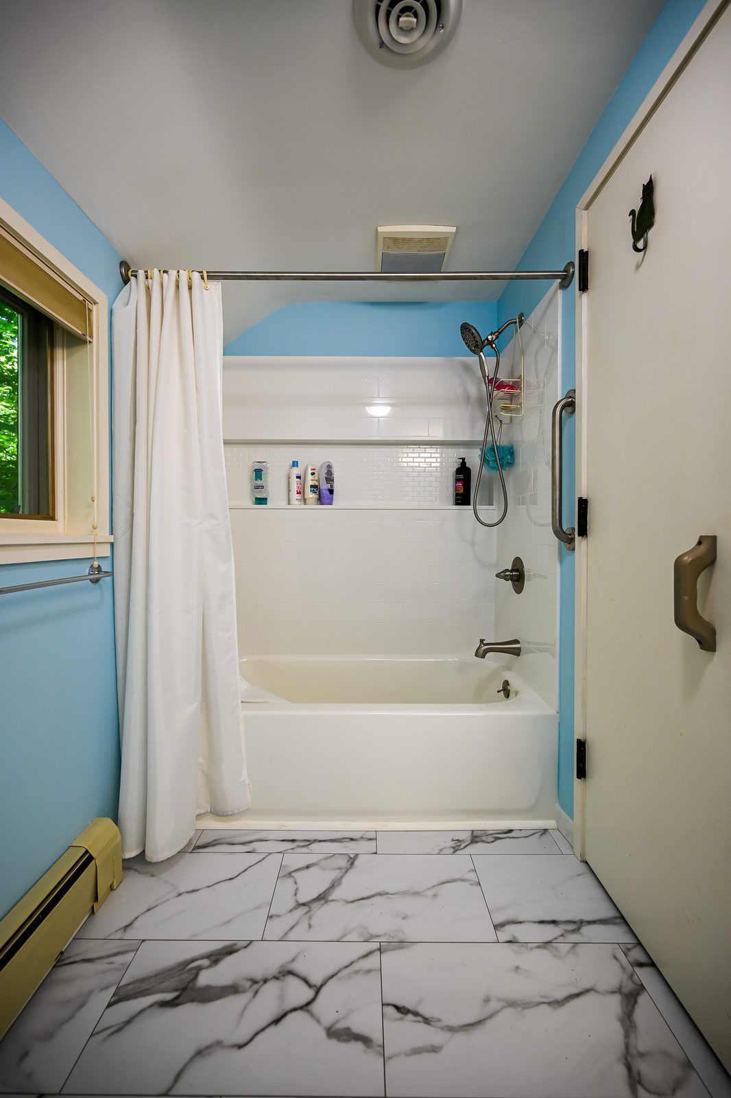 Upstairs Ann Arbor bathroom with blue walls, tub shower and marble-look vinyl plank flooring