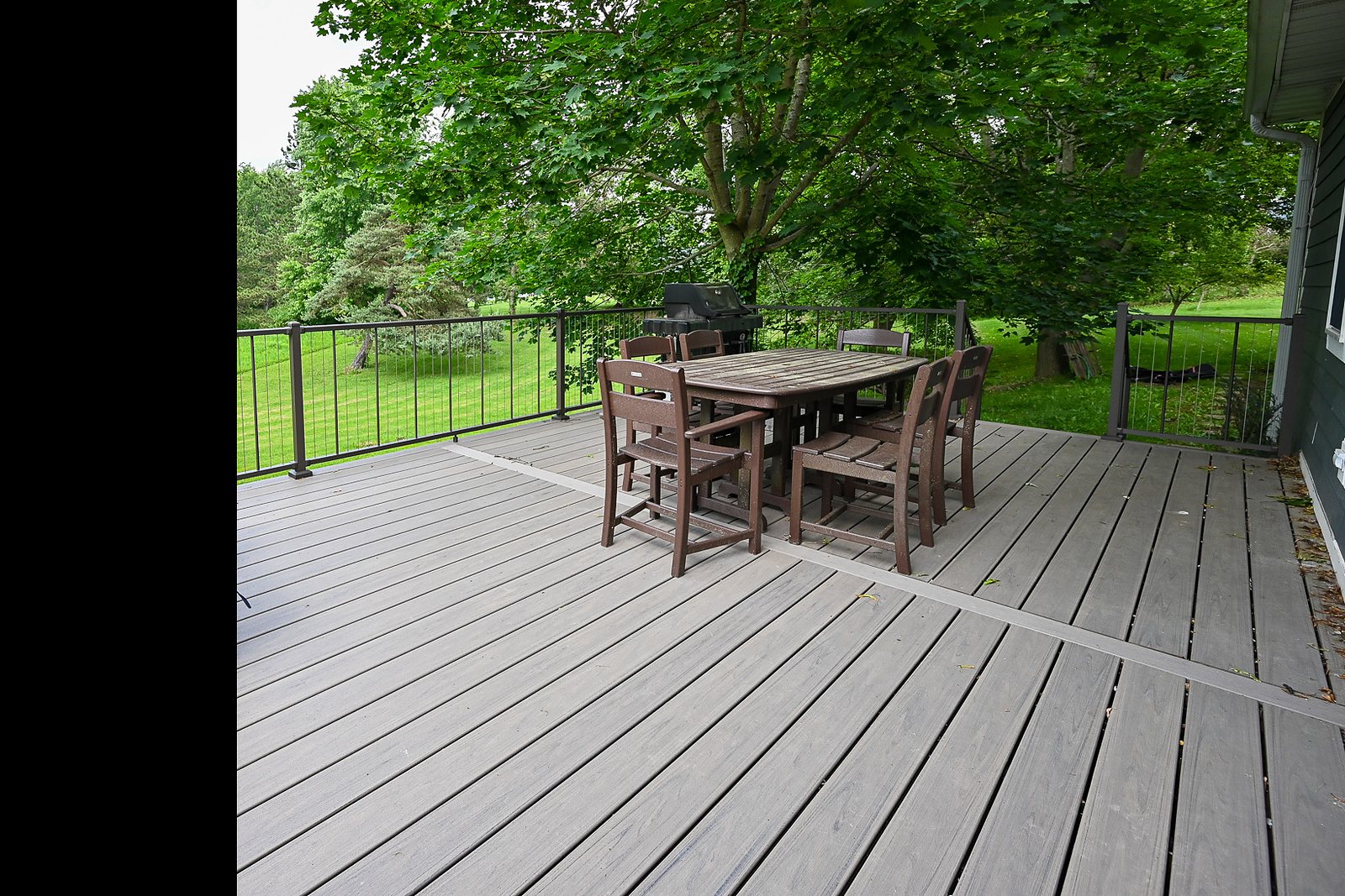 Rebuilt back deck with gray composite boards in a bordered layout and a black metal railing with vertical balusters