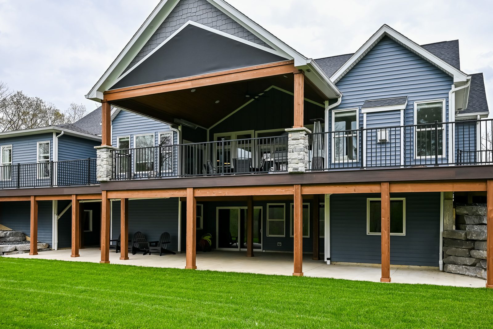 Covered rear porch in Ann Arbor with cedar-wrapped beams beside the home's stone columns