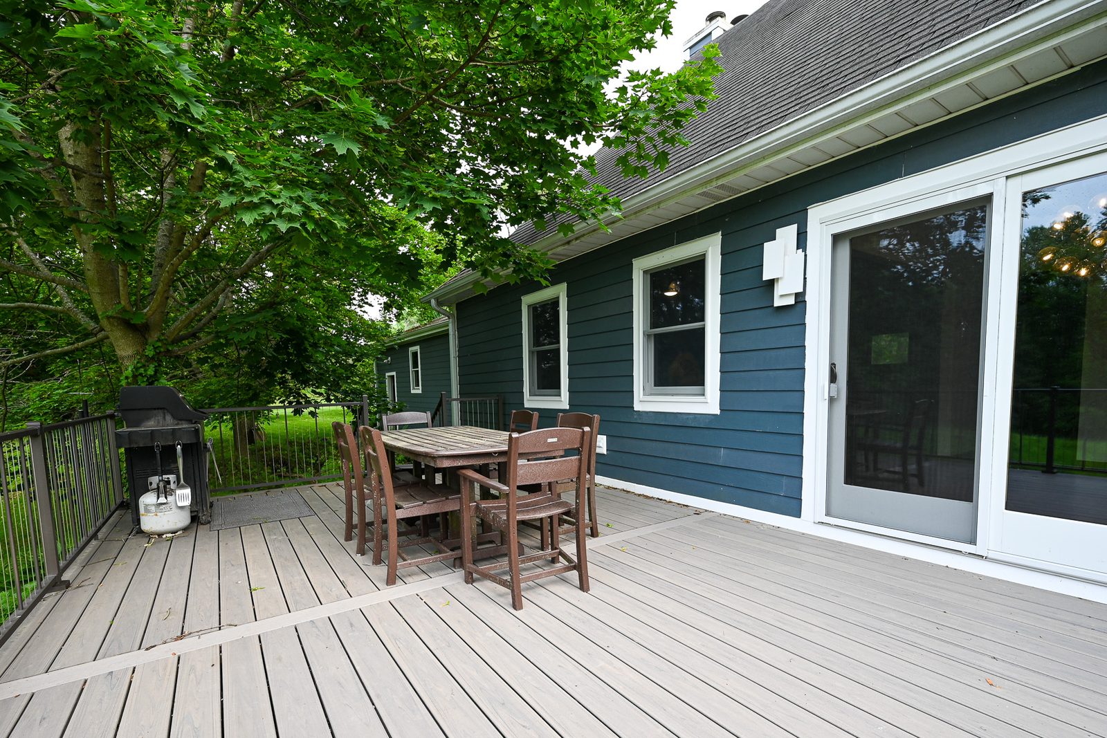 Composite deck and teal blue lap siding at the rear of an Ann Arbor home with a sliding patio door to the kitchen