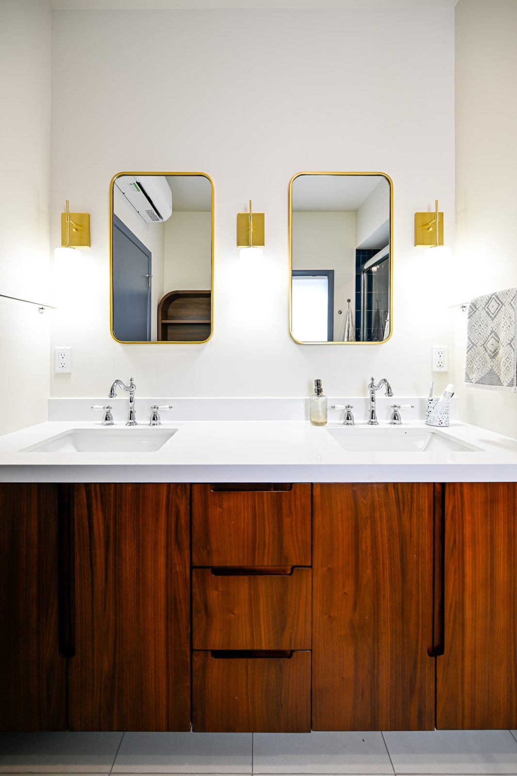 New bathroom with a walnut double vanity and gold mirrors in the Ann Arbor addition