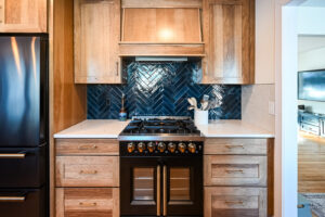 Ann Arbor kitchen with a navy herringbone backsplash, a black range and wood cabinets