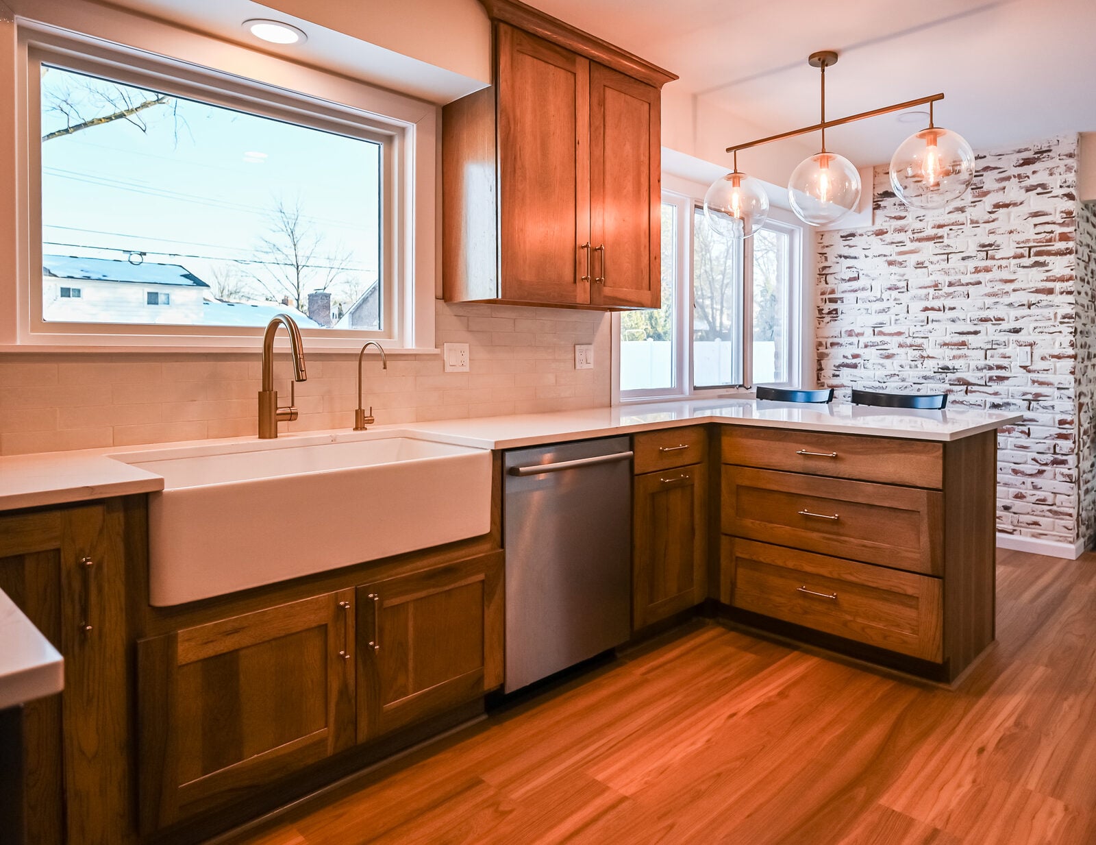 Remodeled Ann Arbor kitchen with a white farmhouse sink under a picture window, quartz counters and a wood-look floor