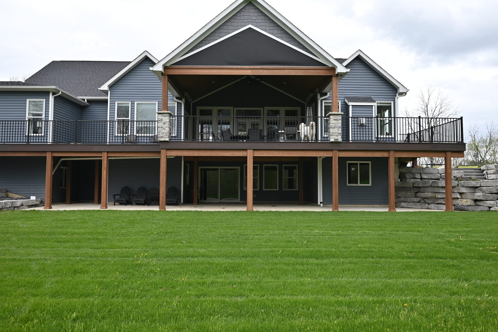 Full rear elevation of an Ann Arbor home showing cedar posts, black deck railing and stone walls