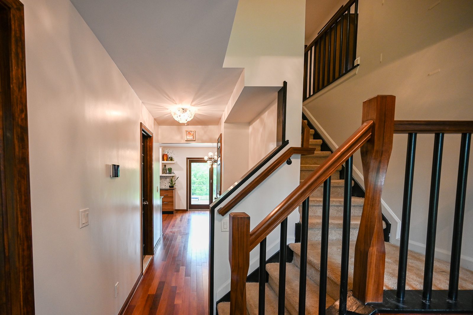 New stair railing with a walnut handrail, sculpted newel posts and black metal balusters above carpeted treads