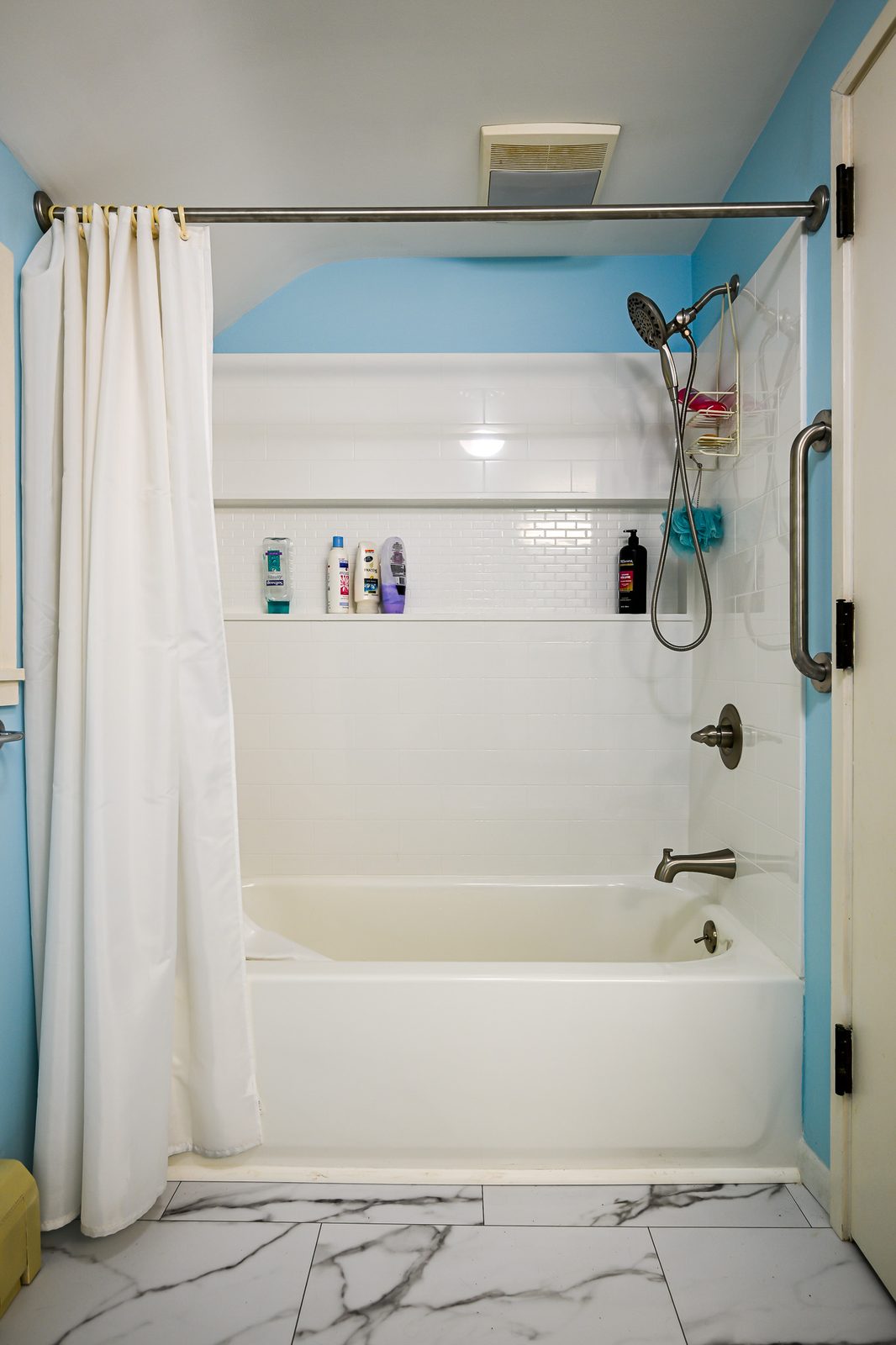 New tub with a white surround and built-in shelf band in a remodeled Ann Arbor bathroom