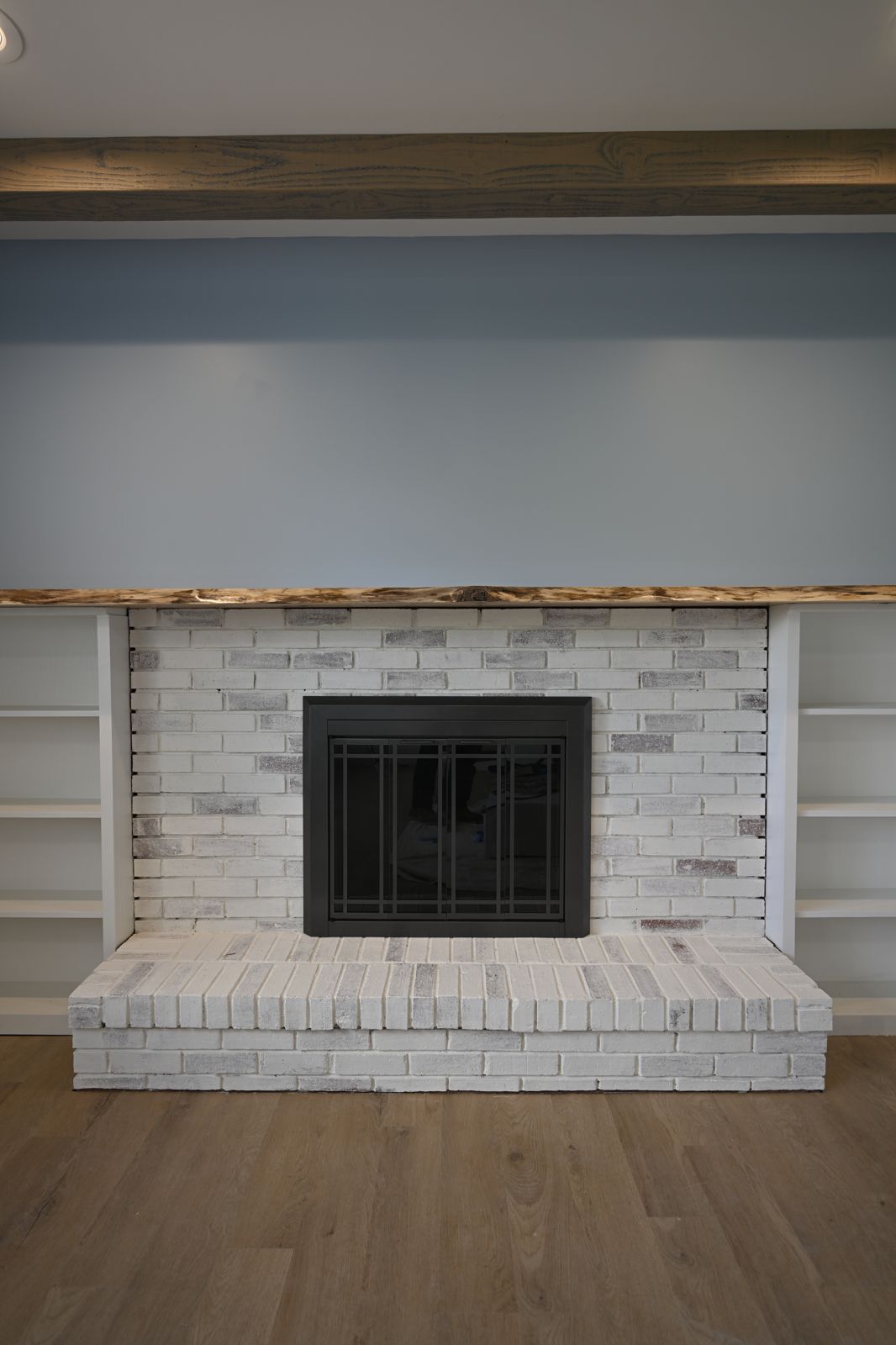 Refinished living room with a white brick fireplace and built-in shelving in Canton