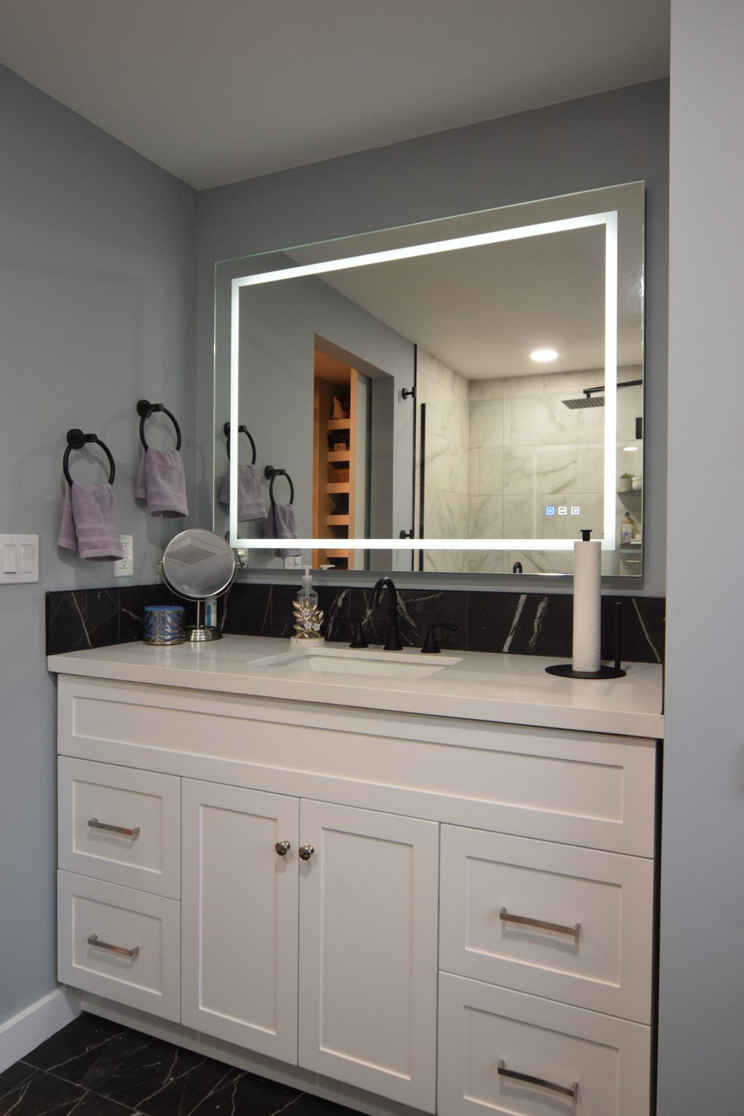 Floating vanity with a backlit LED mirror and matte black faucet in a remodeled Livonia bathroom
