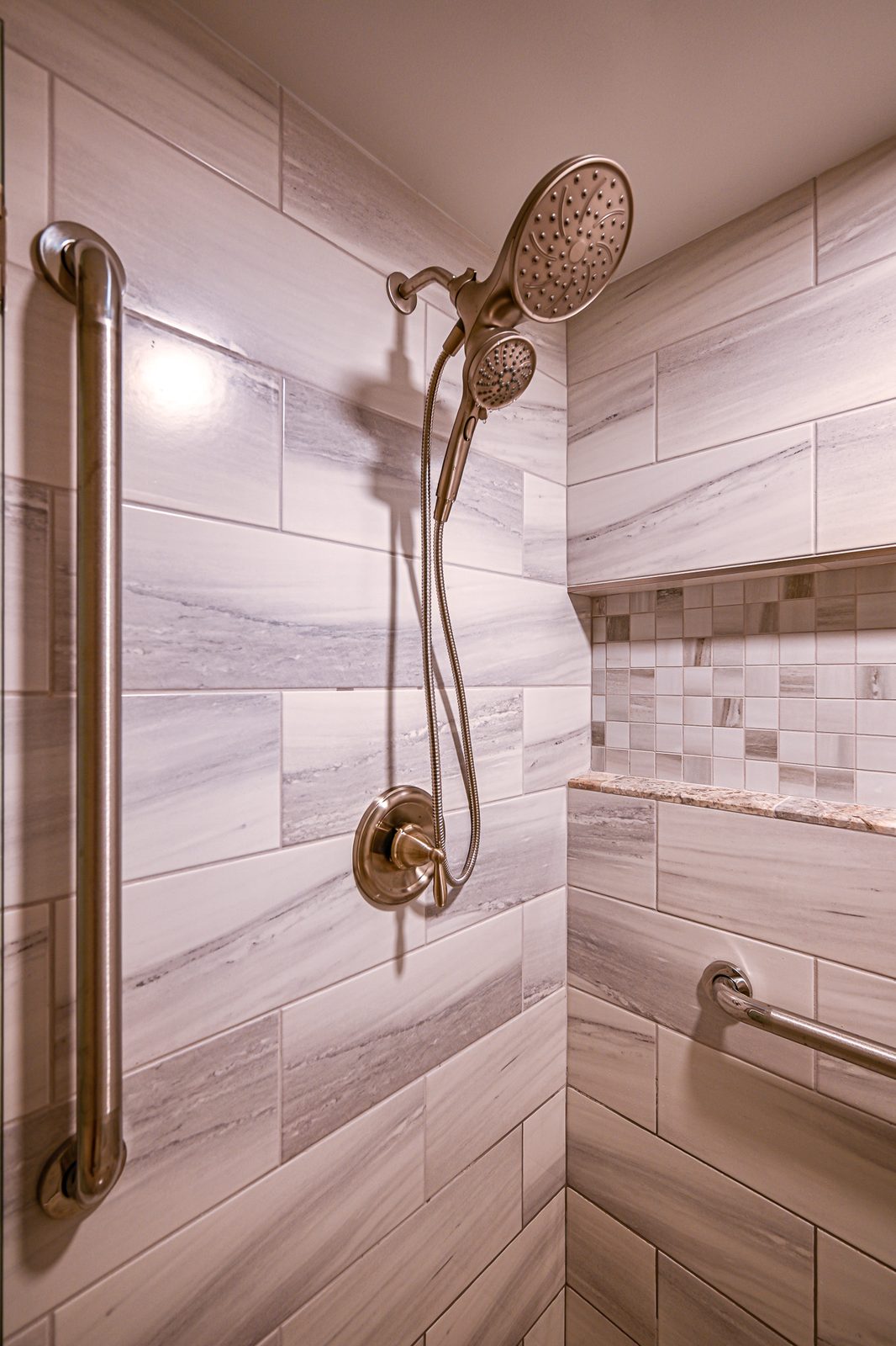 Dual shower heads and a vertical grab bar against large-format tile in a Plymouth walk-in shower