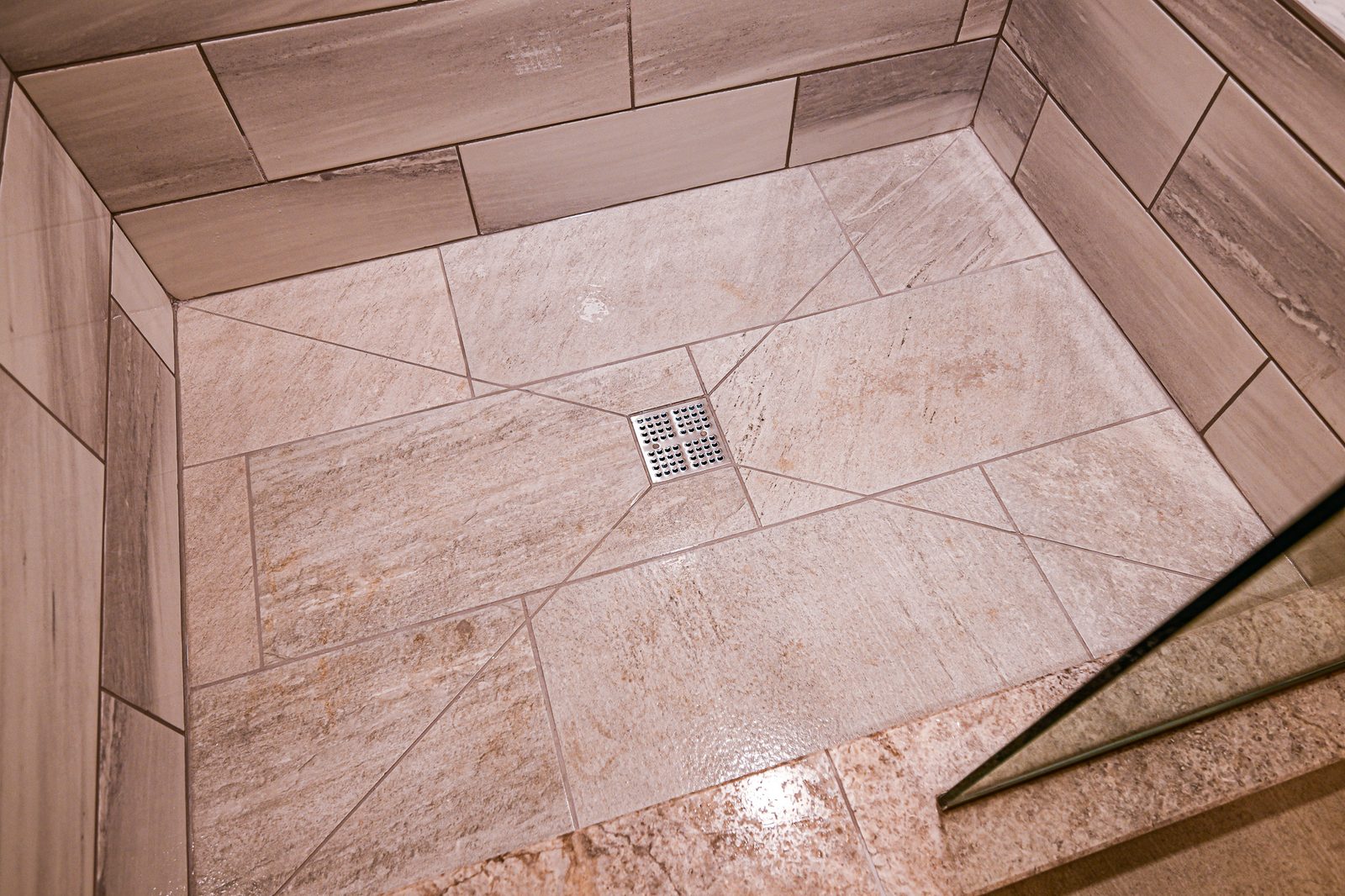 Diagonal-set shower floor tile sloped to a square center drain in a Plymouth walk-in shower