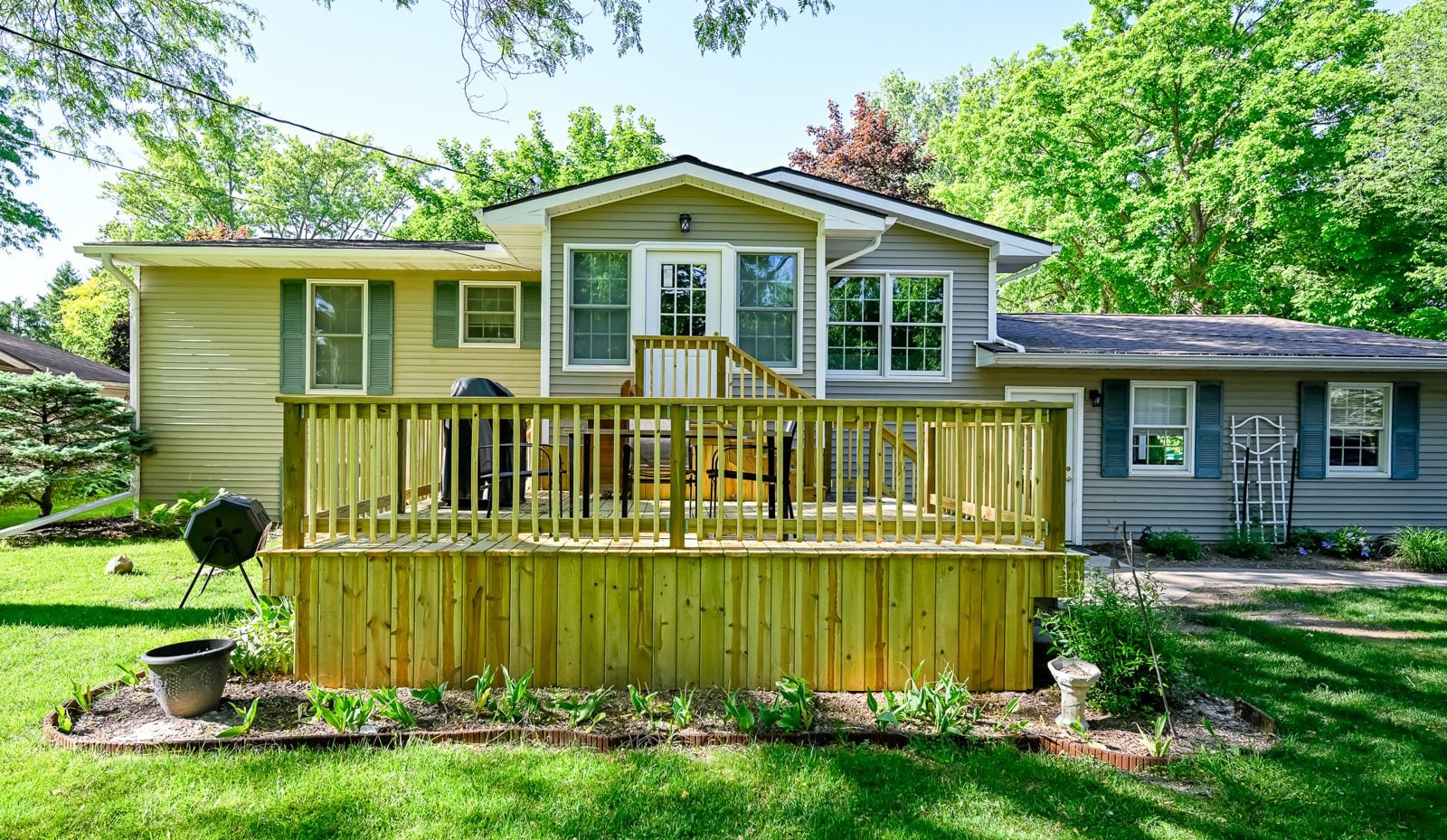Rear exterior of a Saline home with a new mudroom addition, refreshed deck and breezeway to the garage