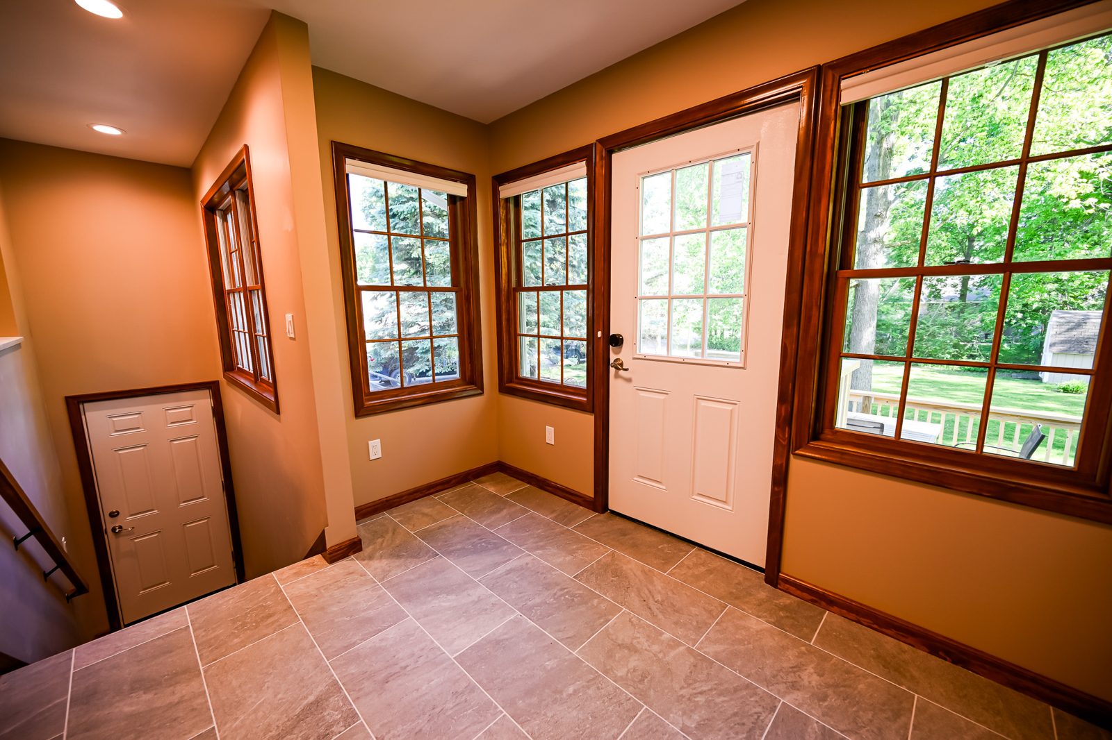 Corner windows and a glass storm door filling the Saline mudroom with daylight