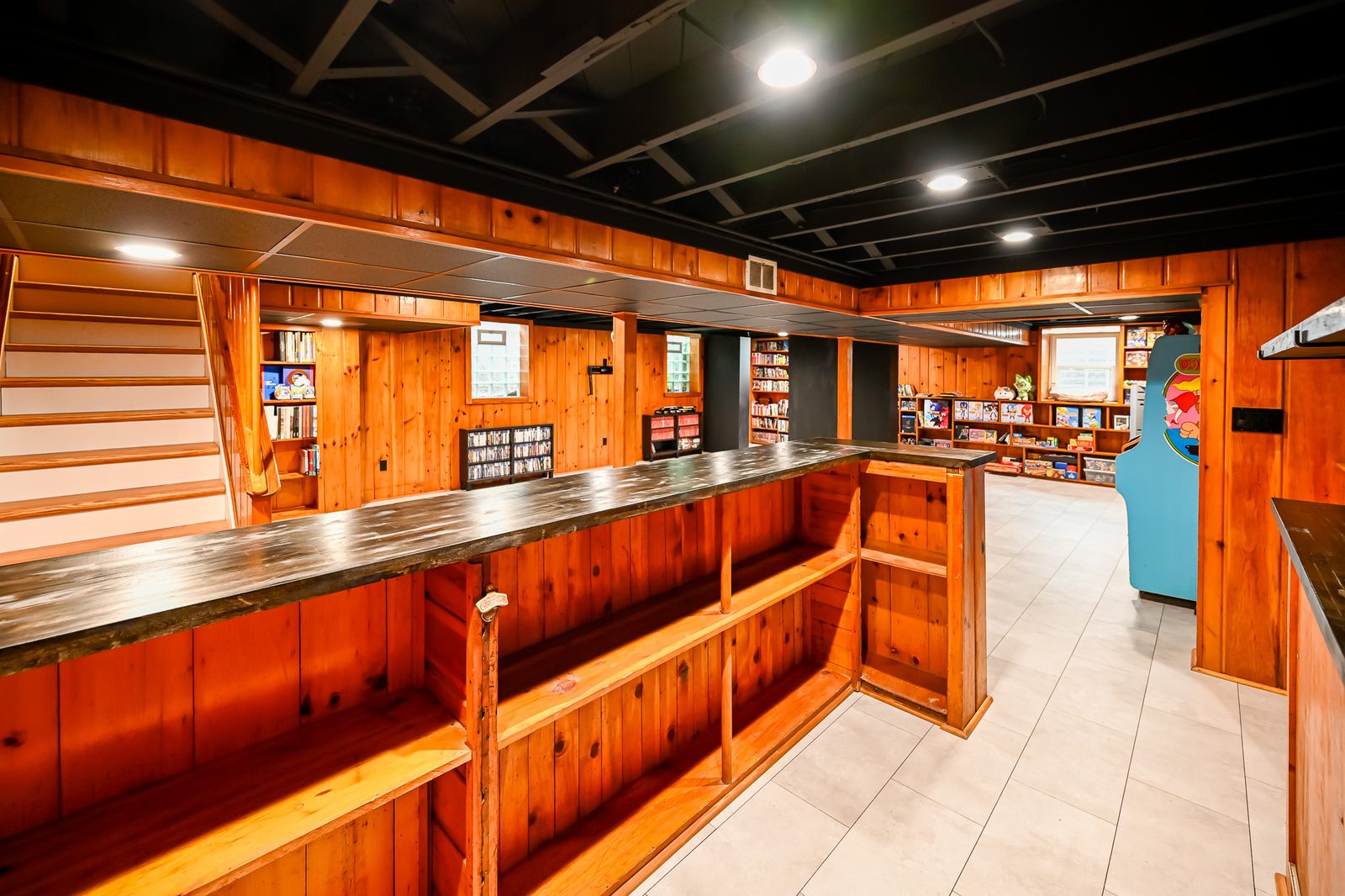 Dark butcher block bar top over knotty pine cabinetry with recessed lighting in an Ypsilanti basement