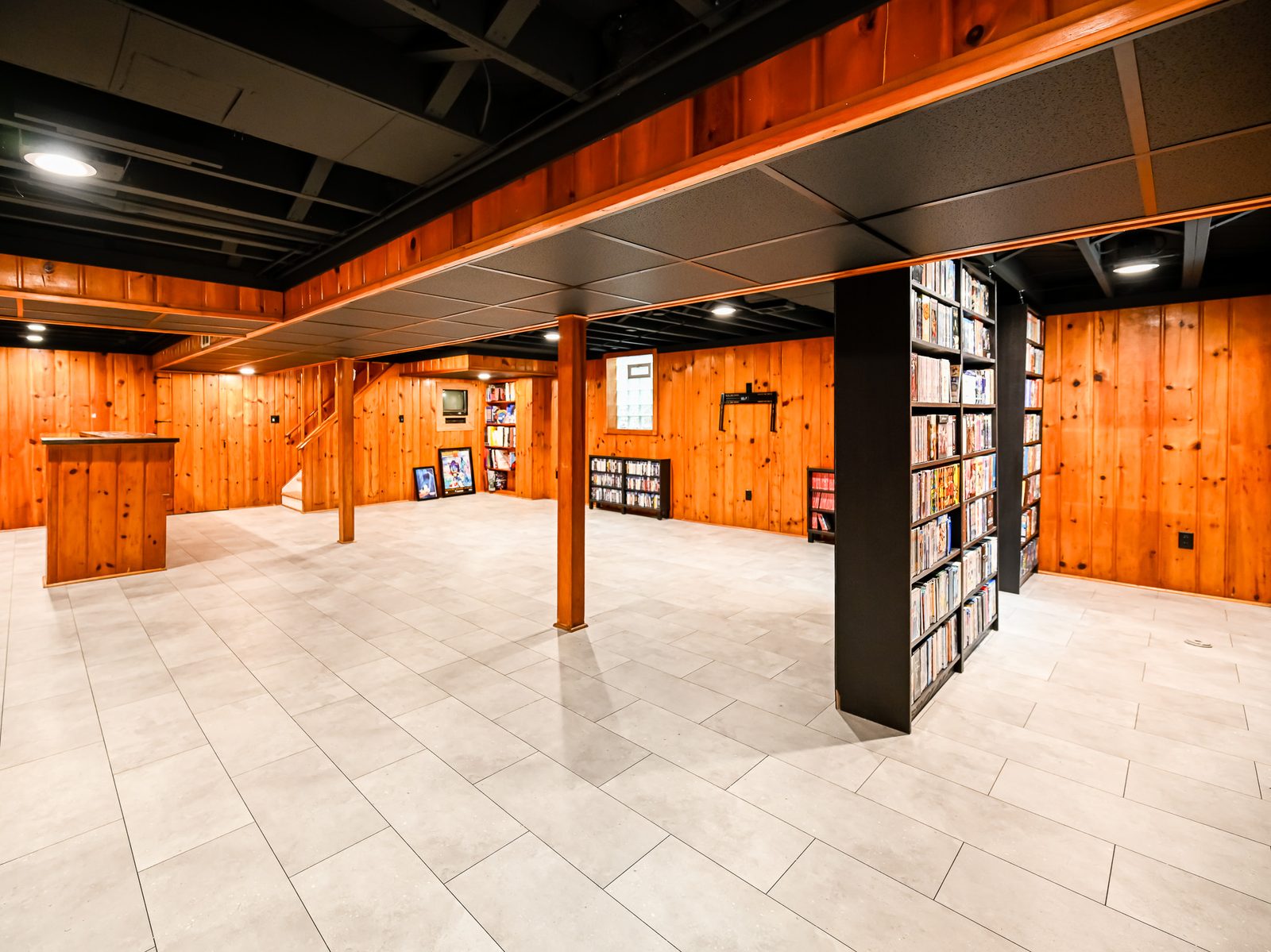 Open finished basement floor with built-in media shelving and light tile in Ypsilanti