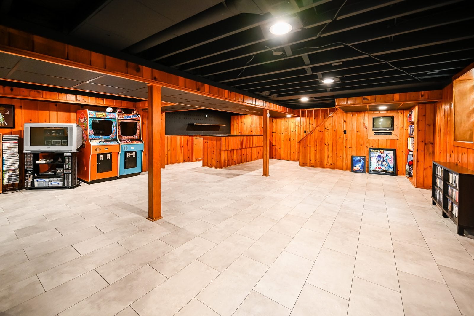 Finished basement game room in Ypsilanti with knotty pine walls and a black ceiling