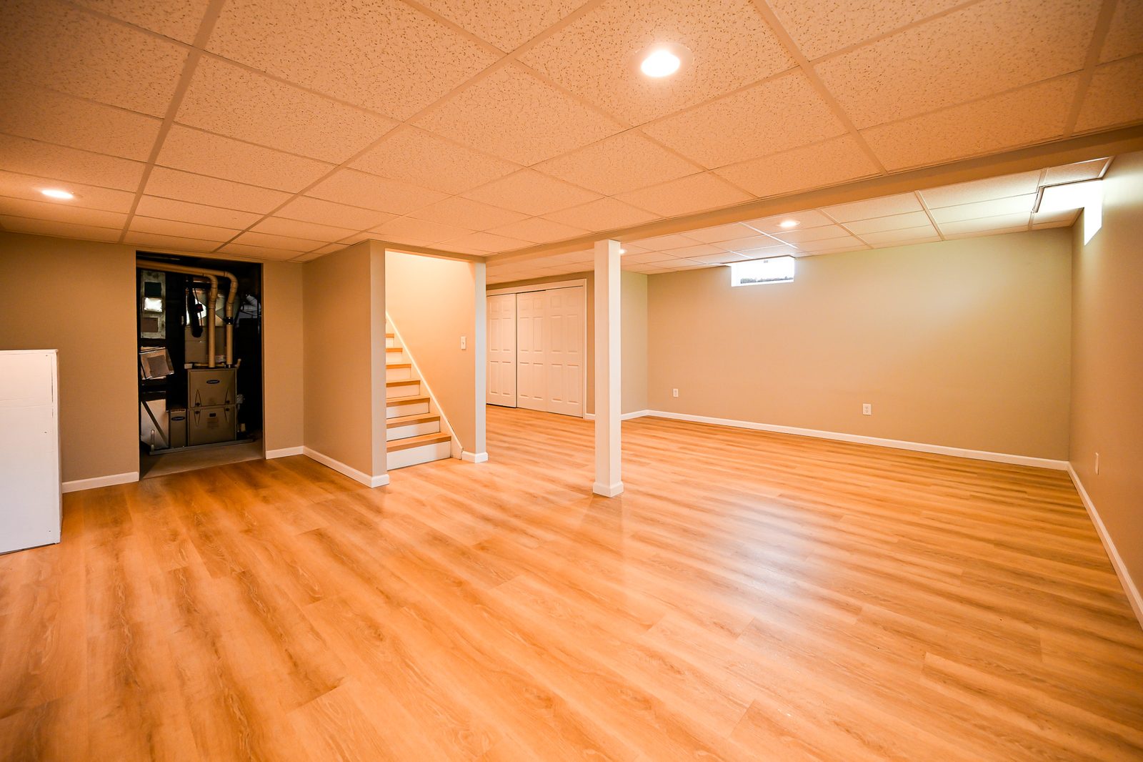 Wide view of the refinished Ypsilanti basement showing the stairs and tucked-away mechanical closet