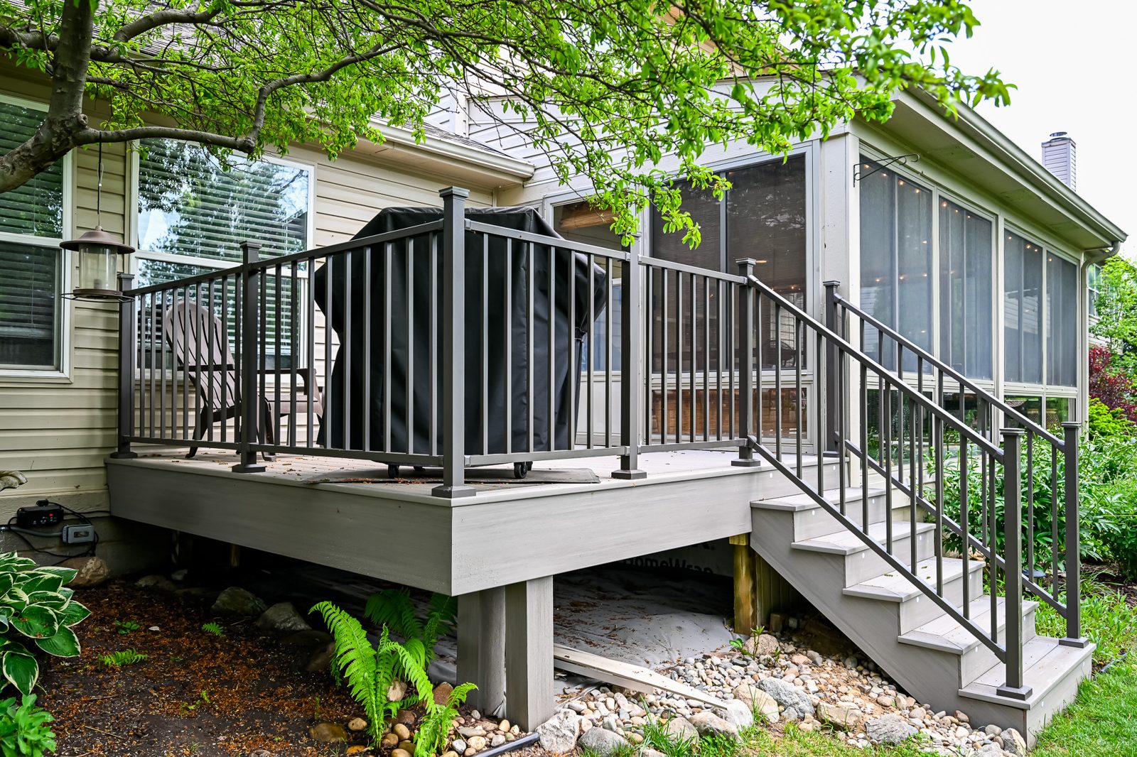 Composite deck re-top with dark railings behind a remodeled Ypsilanti porch