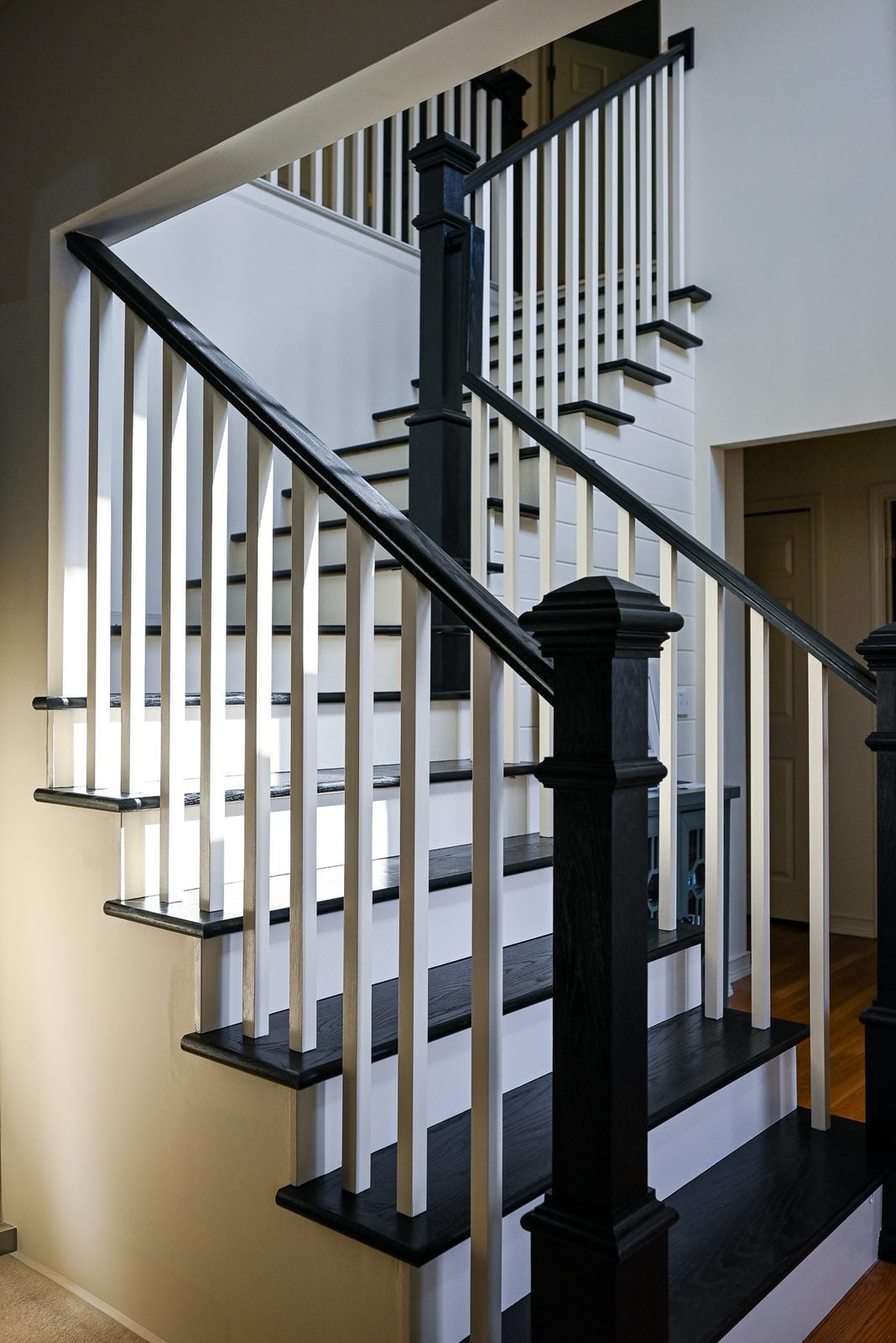 Rebuilt staircase in an Ypsilanti home with black oak treads, cream risers, white balusters and black newel posts