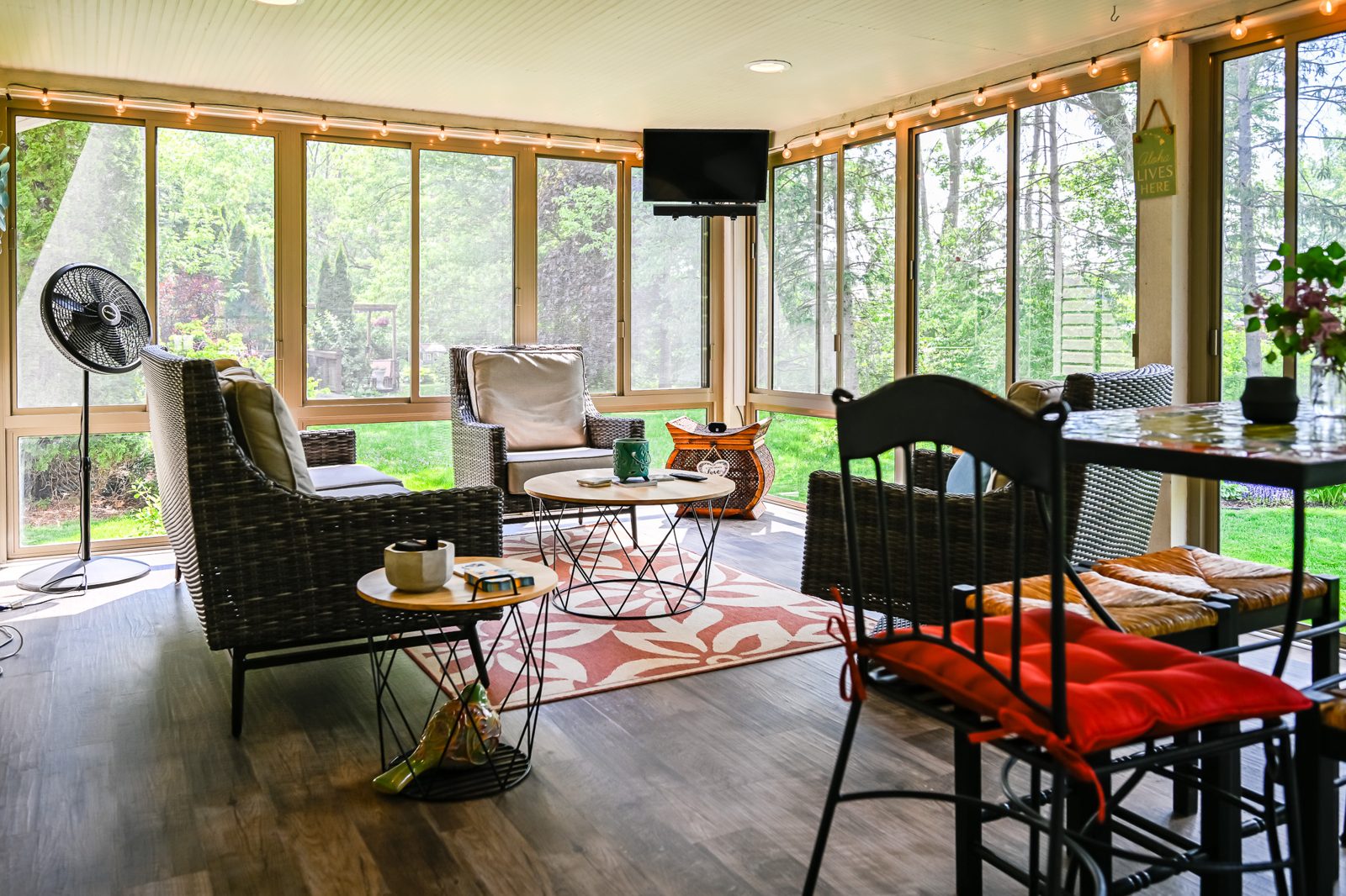 Three-season porch interior in Ypsilanti with string lights, new plank floor and screened windows