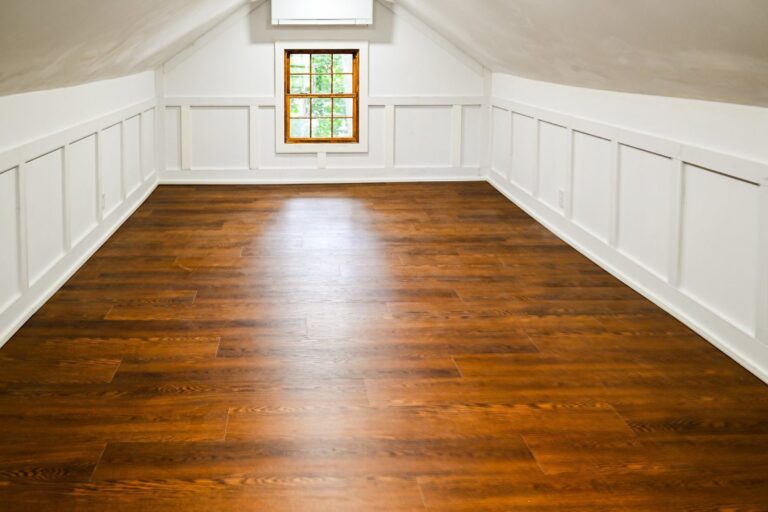 Finished attic in Ann Arbor with white wainscoting, sloped ceilings, a gable window and new hardwood flooring
