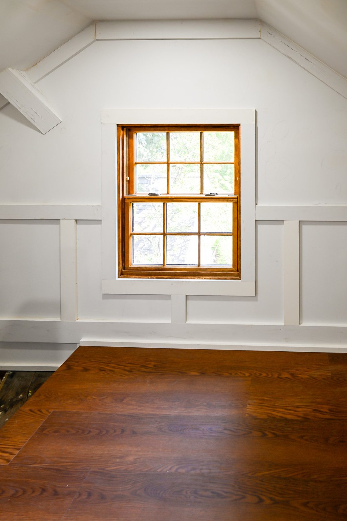 Gable window centered in a finished Ann Arbor attic with white trim and wood flooring