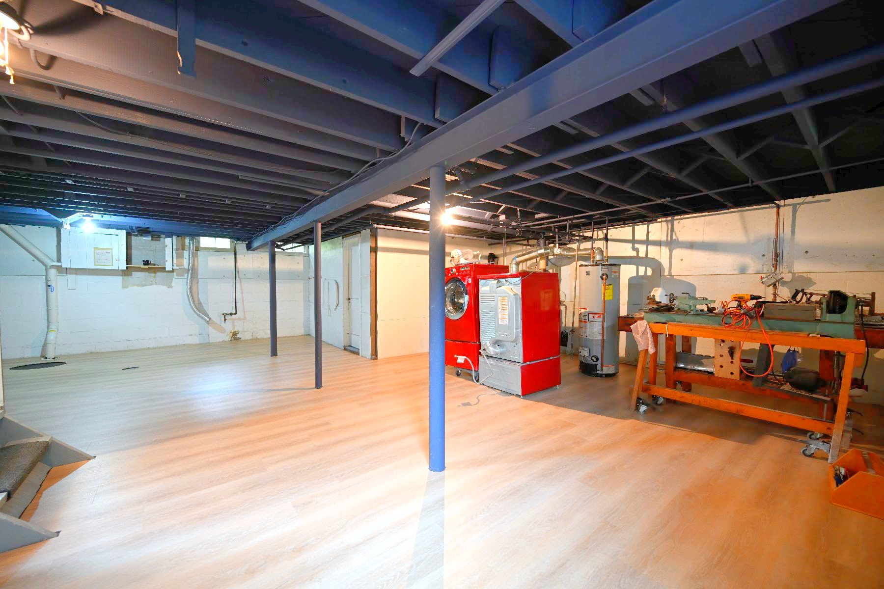 Open basement area in Ann Arbor with painted steel lally columns, boiler and workbench under a black sprayed ceiling