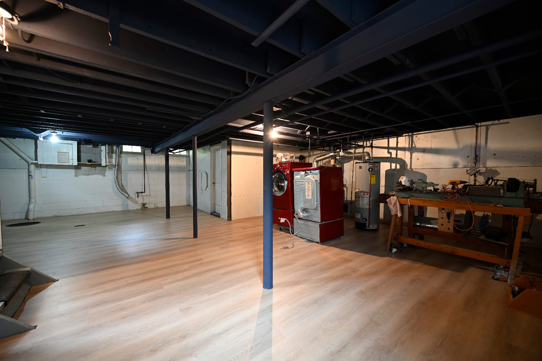 Open basement area in Ann Arbor with painted steel lally columns, boiler and workbench under a black sprayed ceiling