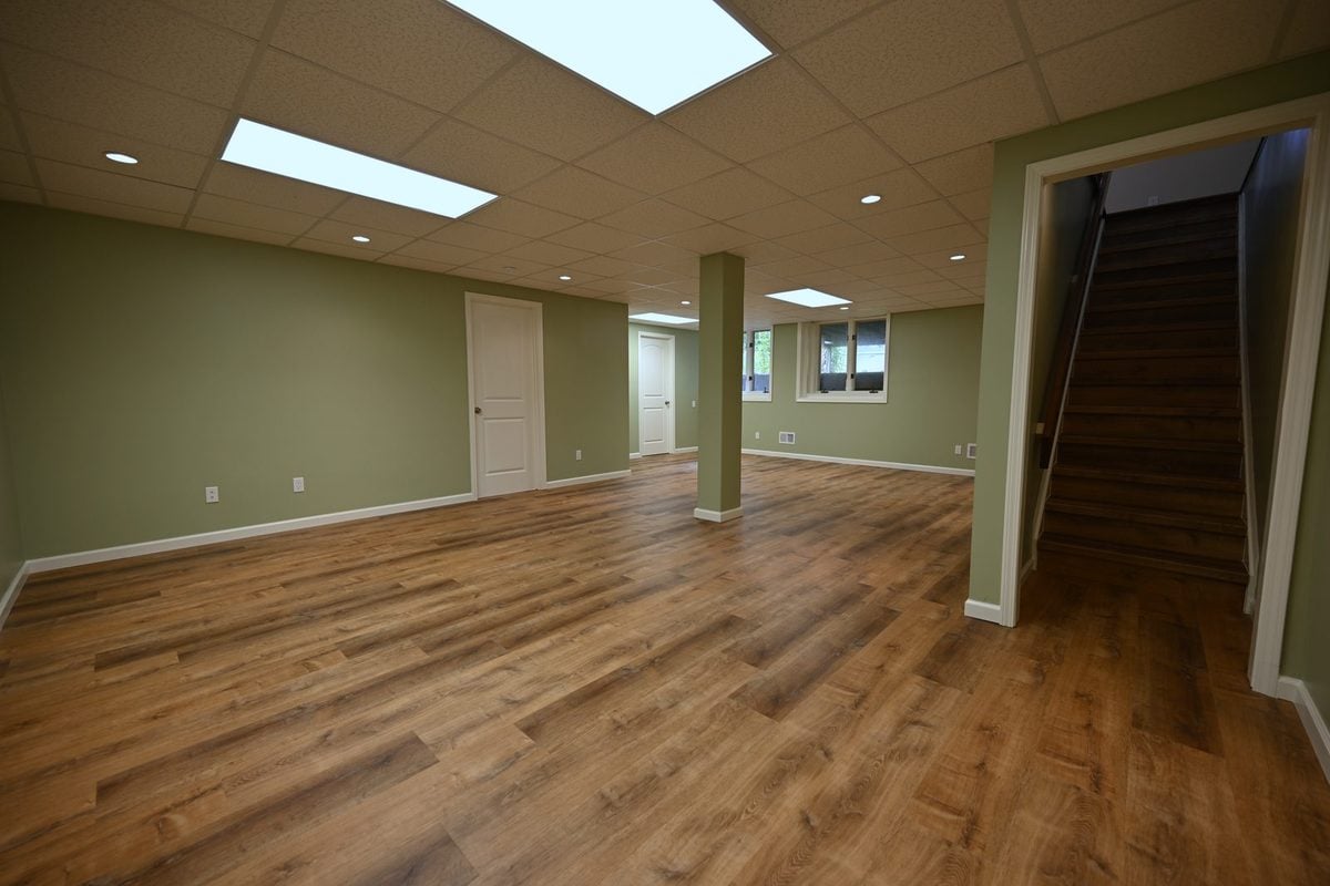 Finished basement rec room in Ann Arbor with sage green walls and wide plank luxury vinyl flooring