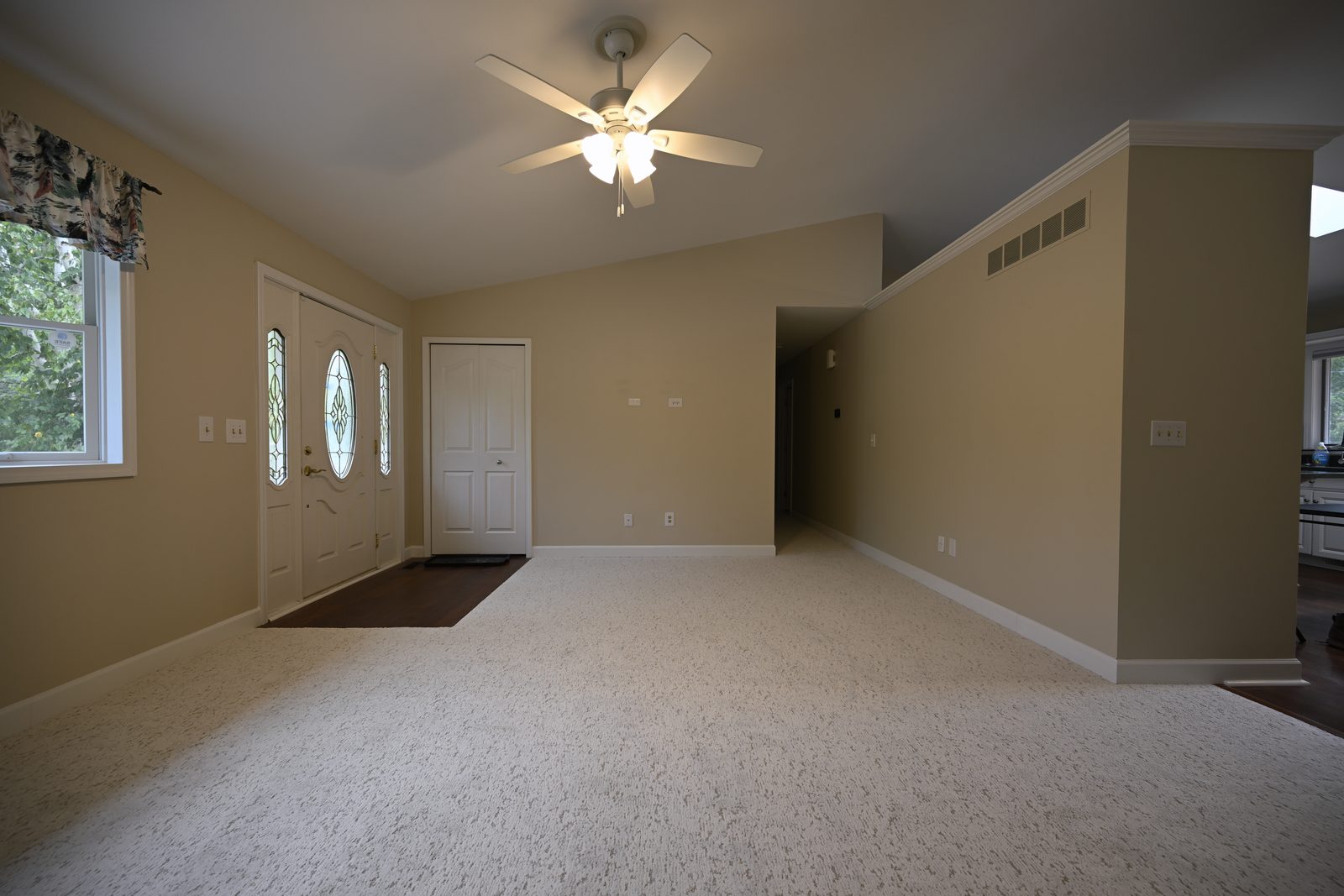 Main floor living area of an Ann Arbor home with new low pile cream carpet meeting dark hardwood at the entry and a leaded glass front door