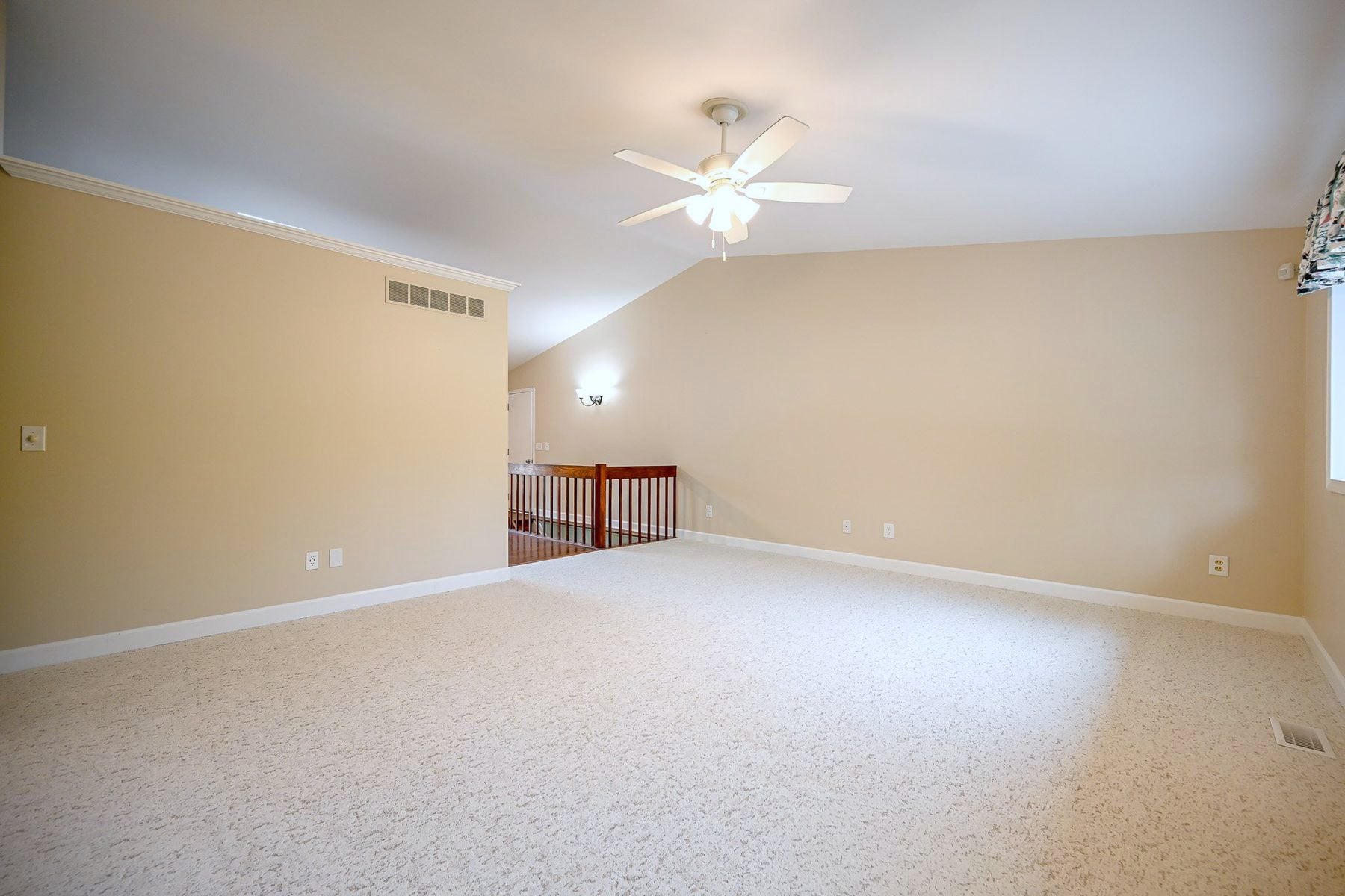 Main floor living area of an Ann Arbor home with new low pile cream carpet meeting dark hardwood at the entry and a leaded glass front door