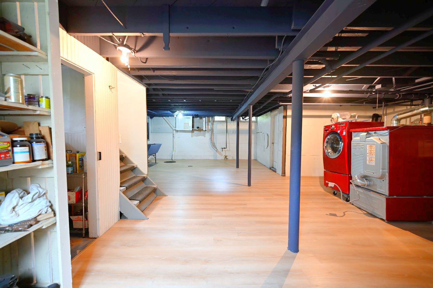 Basement laundry area beside the stairs with plank flooring running through to the far wall