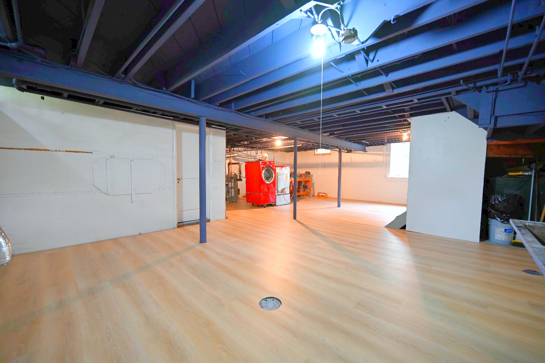 Wide view of the finished Ann Arbor basement showing the full plank floor and black ceiling across the open room