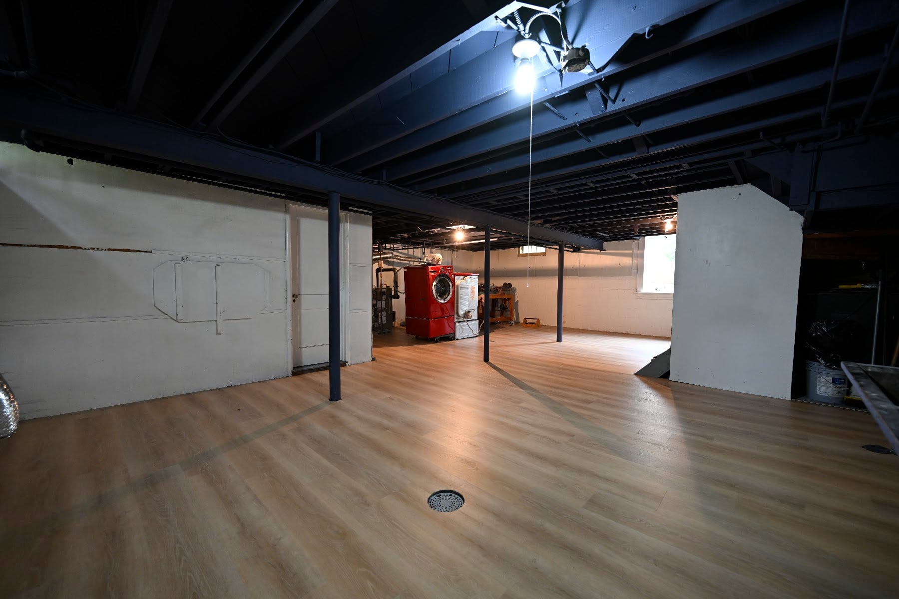 Wide view of the finished Ann Arbor basement showing the full plank floor and black ceiling across the open room