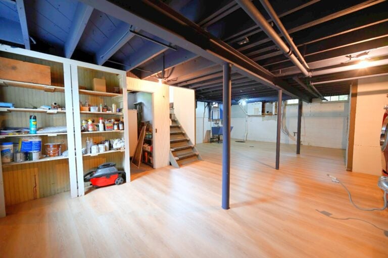 Finished Ann Arbor basement with a light plank floor, black sprayed ceiling and original built-in wood shelving