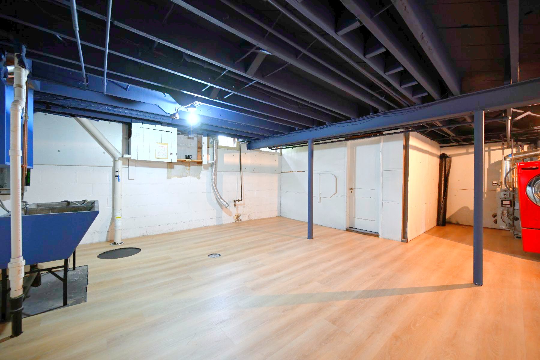Basement storage rooms with white doors, painted block walls and new plank flooring running to the threshold